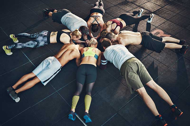 Young people focused on planking in a circle in a gym