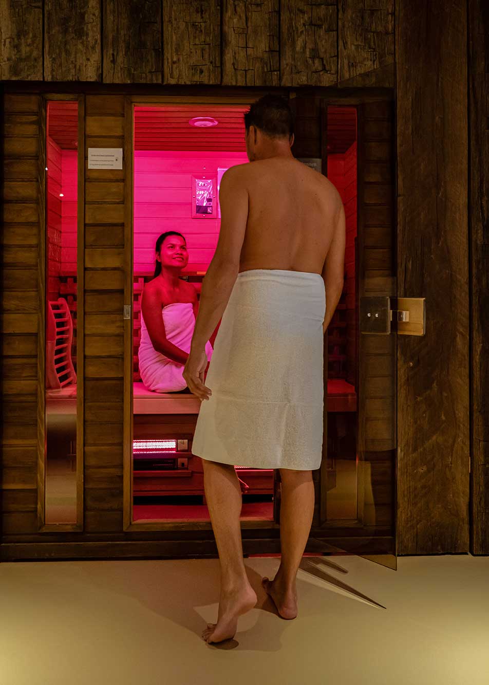 Couple in a sauna, men and woman in bathrobe visiting a hot infrared sauna indoor