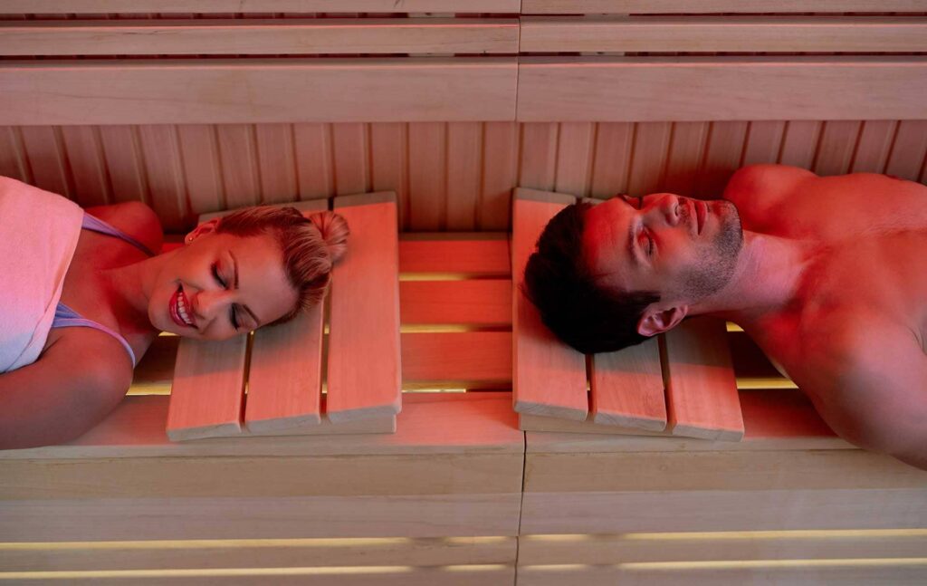 High-angle view of a couple relaxing with eyes closed while in an infrared sauna at a health spa.