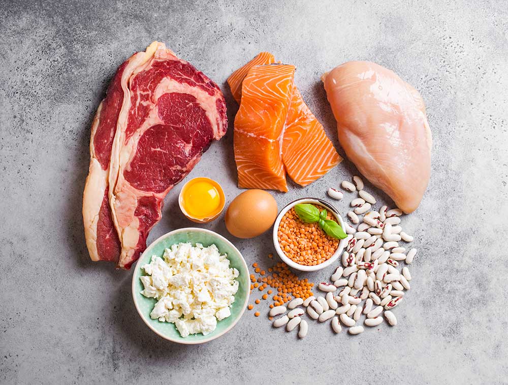 Assortment of natural sources of protein from food: meat, fish, chicken, dairy products, eggs, beans. Diet, healthy eating, wellness, bodybuilding concept, top view, stone background.