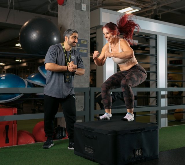 a gym member does box jumps during a workout with a personal trainer at golds gym in vancouver